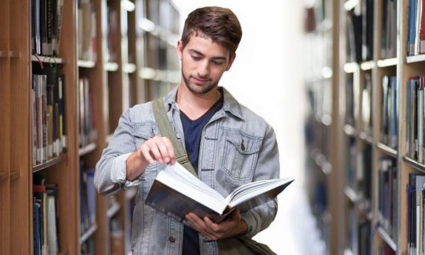 Chico buscando en un libro en una biblioteca